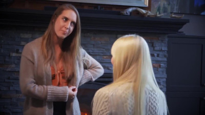 Kenna James and Cadence Lux on a floor next to a fireplace and grey sofa lesbian