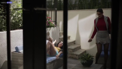 Penny Barber and Alex Coal on a grey sofa and a grey chair in several lesbian scenes